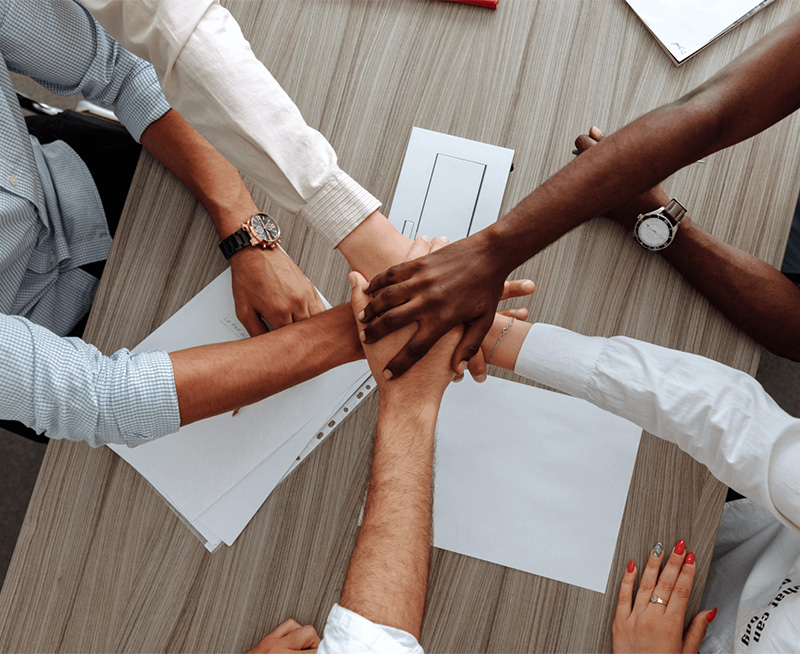 An overhead shot of a group of diverse people with their hands together